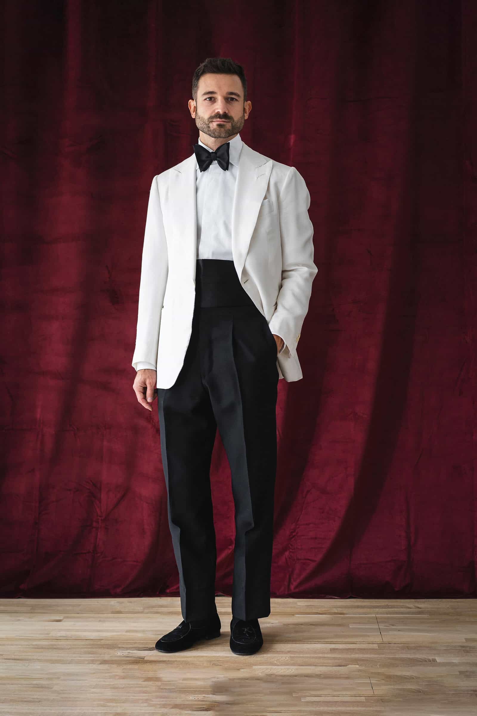 Cremefarbenes Maß-Smokingjackett, schwarze Hochbund-Hose und Samt-Loafer