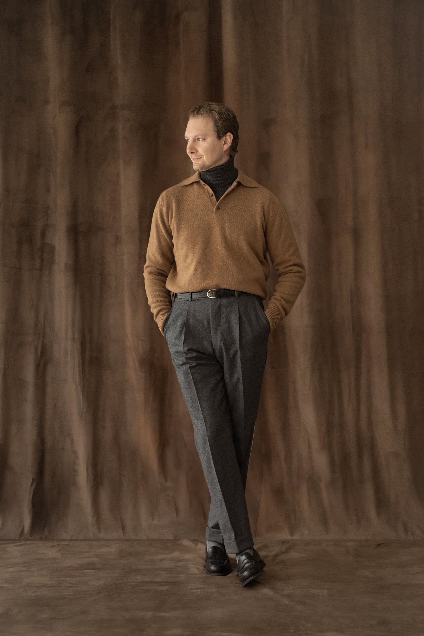 Strickpolo in Camel über dunkelgrauem Rollkragen, dazu graue Bundfaltenhose