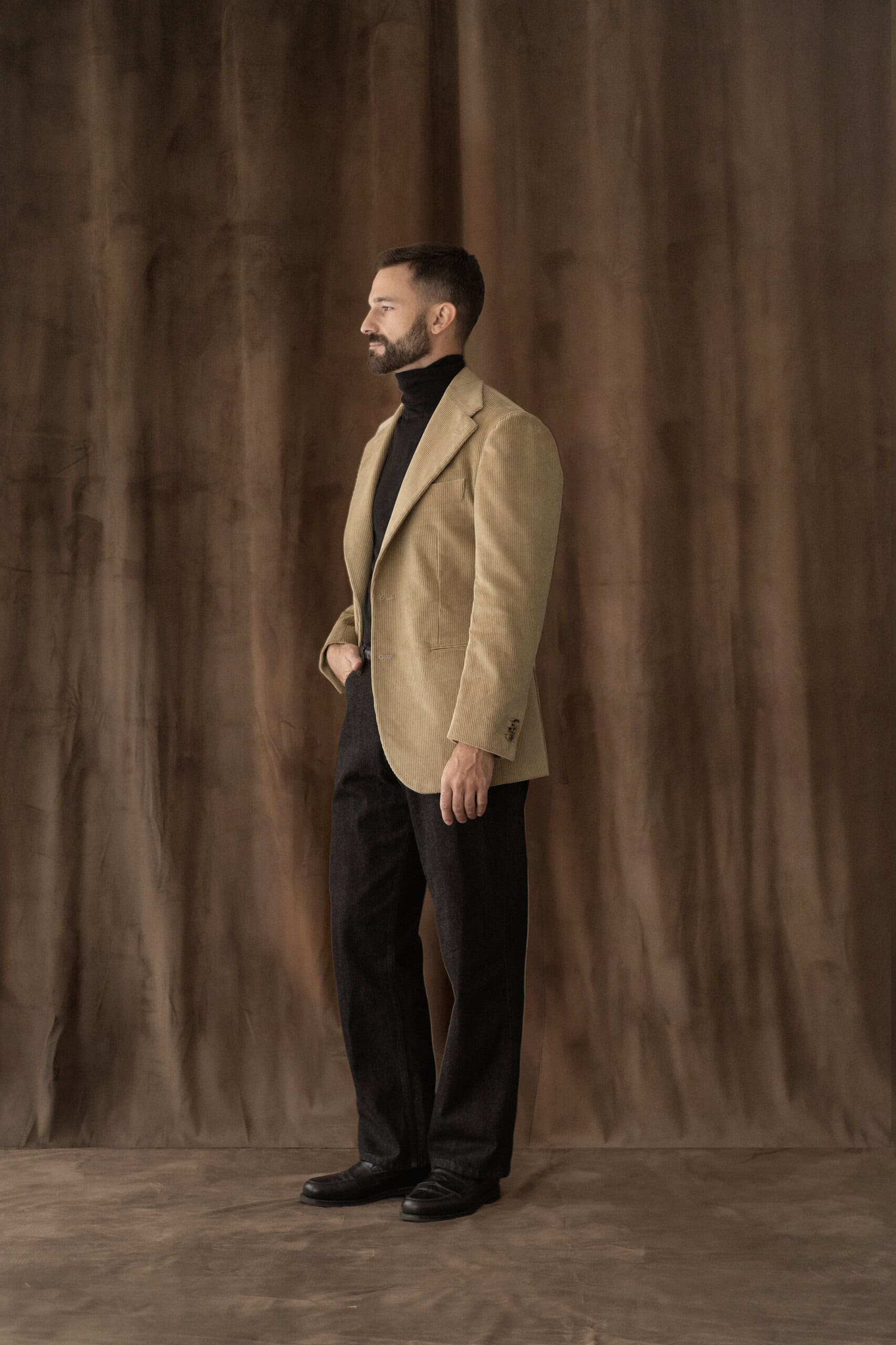 Sakko in Sand mit schwarzem Rollkragenpullover und dunkler Hose